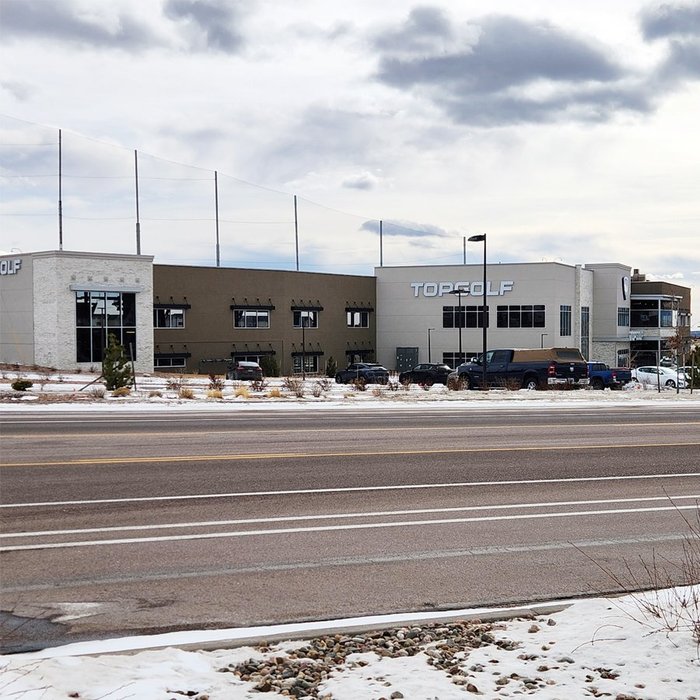Completed Topgolf building exterior with two-story storefront glazing on a winter day